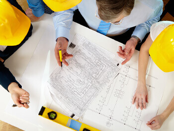 Overhead view of serval electrical contractors reviewing blue prints